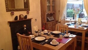 A dining area with a fireplace, wooden furniture, and a view of the outdoors. - Heathfield B&B Guest House (Whitby)