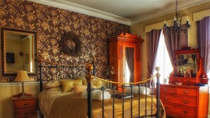 A bedroom with a four-poster bed, a wooden dresser, a mirror, and a chandelier. - Heathfield B&B Guest House (Whitby)