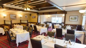 A restaurant with multiple tables set for dining, wooden beams on the ceiling, and a plaid carpet. - The Ellerby Country Inn (Saltburn-by-the-Sea)