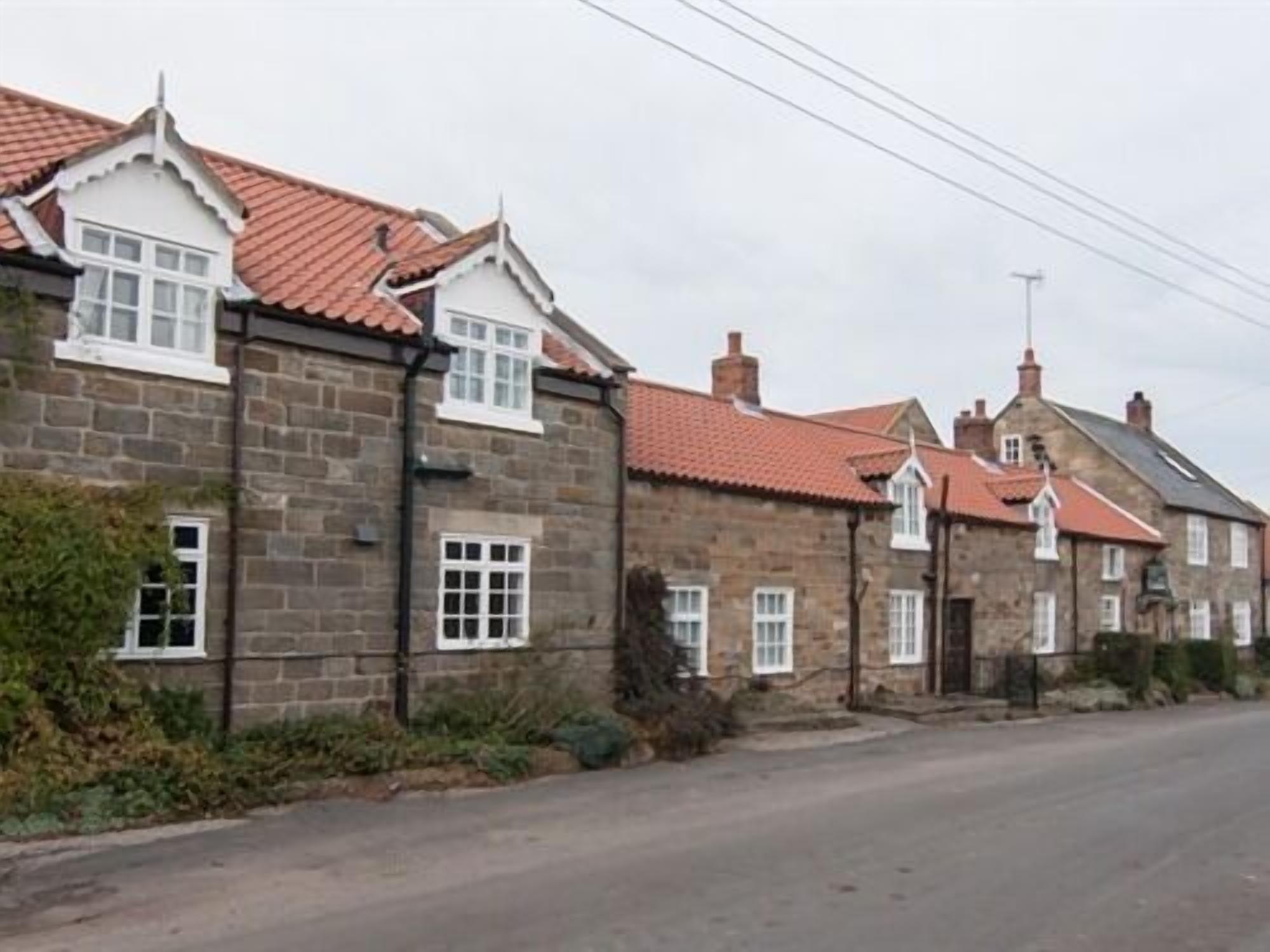 A row of stone houses with red-tiled roofs and white window frames.