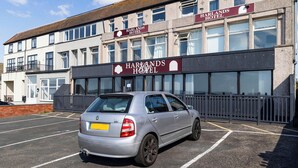 A silver car parked in a parking lot in front of Harlands Hotel. - Harlands Hotel (Blackpool)