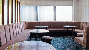 A modern lounge area with a curved sofa, round tables, and a patterned carpet. - Harlands Hotel (Blackpool)