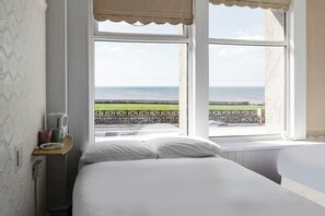 Enjoy a serene sea view from the large window, with a comfortable bed and a convenient shelf for your essentials.