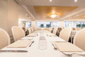A conference room with a long table set for a meeting, equipped with chairs and tables, and a chandelier on the ceiling. - Hotel Paradis (Lourdes)