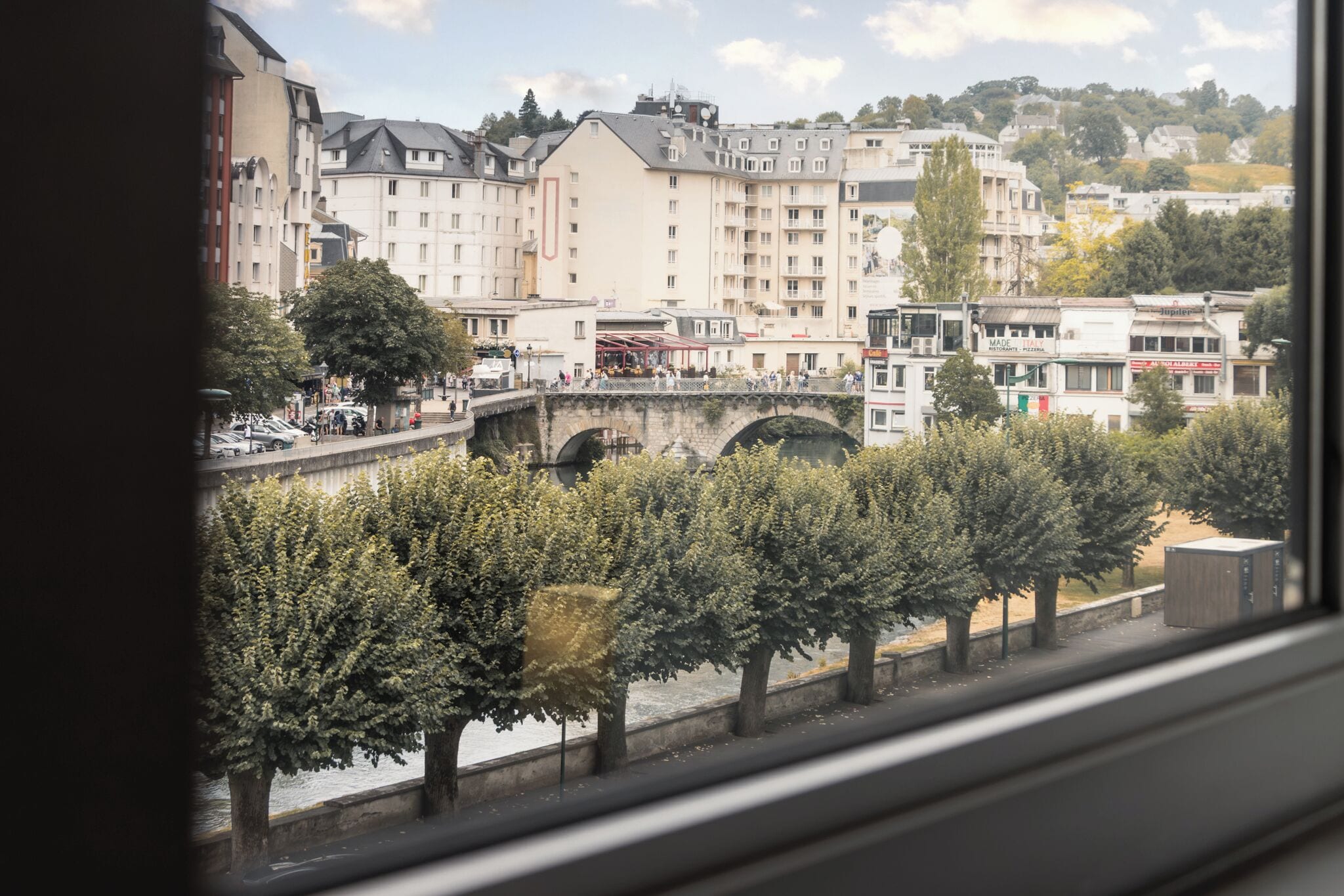 A view of a river with a bridge, buildings, and trees.