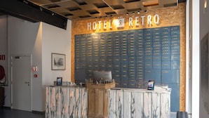 A hotel reception desk with a marble counter, a Lenovo computer, and a wall of blue lockers. - Hotel Retro (Brussels)