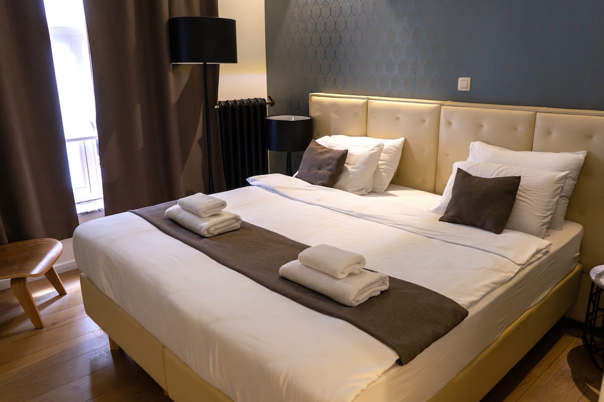 A hotel room with a large bed, a bedside lamp, and a view of the outside.