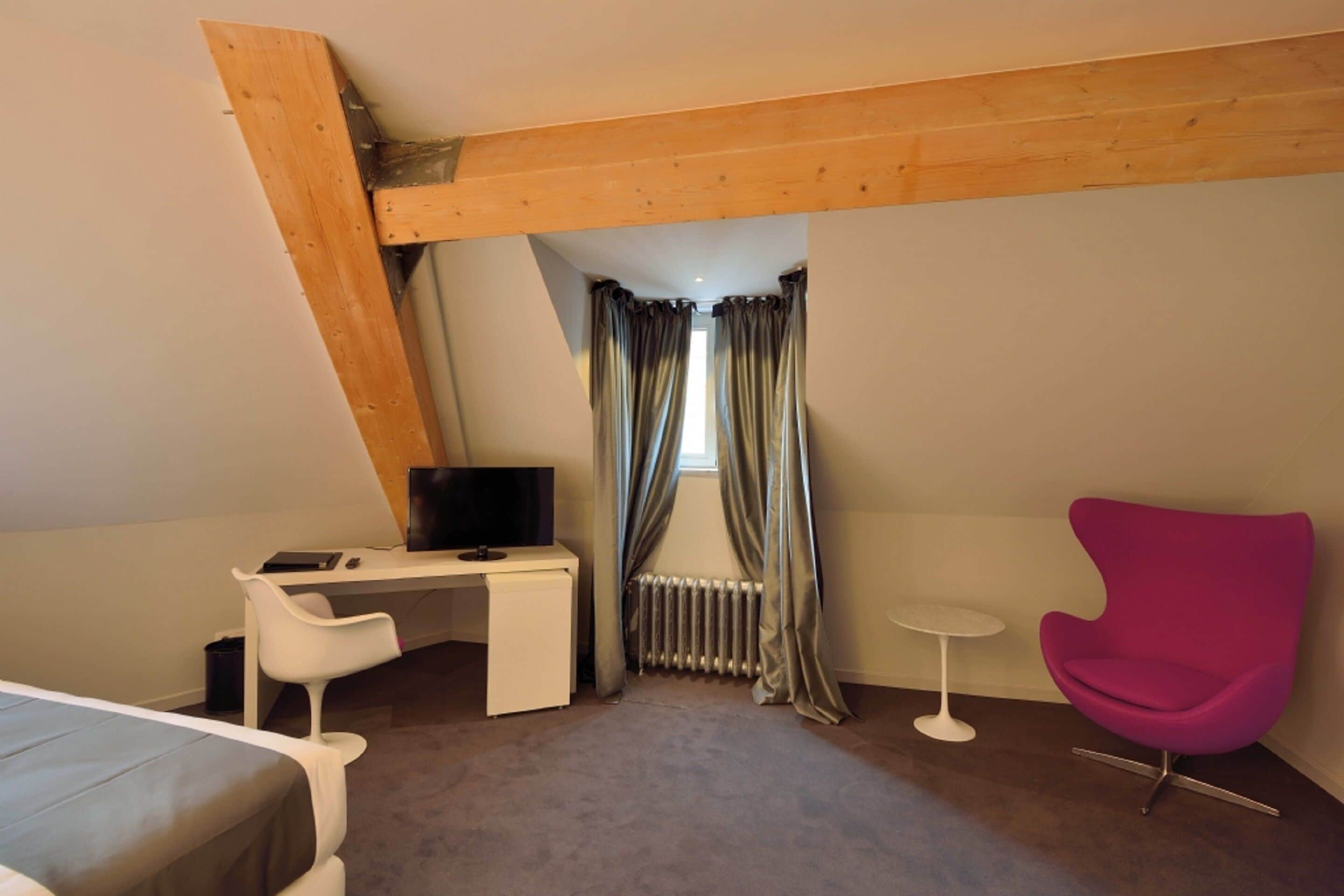Ein Schlafzimmer mit einem Bett, einem Schreibtisch, einem Stuhl, einem Fernseher und einem Fenster mit Vorhängen.