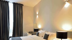 A hotel room with a bed, bedside table, lamp, and a chair. - Hotel Retro (Brussels)