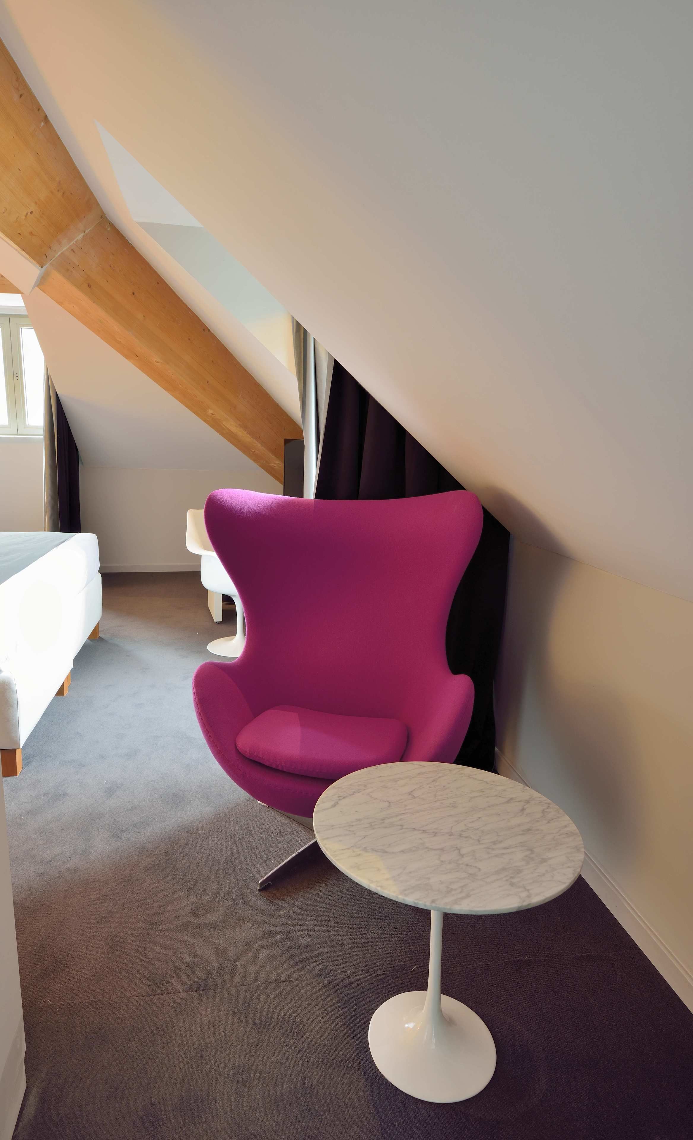 A modern room with a purple chair, a small round table, and a bed.