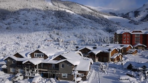 A snow-covered mountain village with wooden cabins and a red building, likely a hotel or resort. - Ski Sur Apartments (San Carlos de Bariloche)