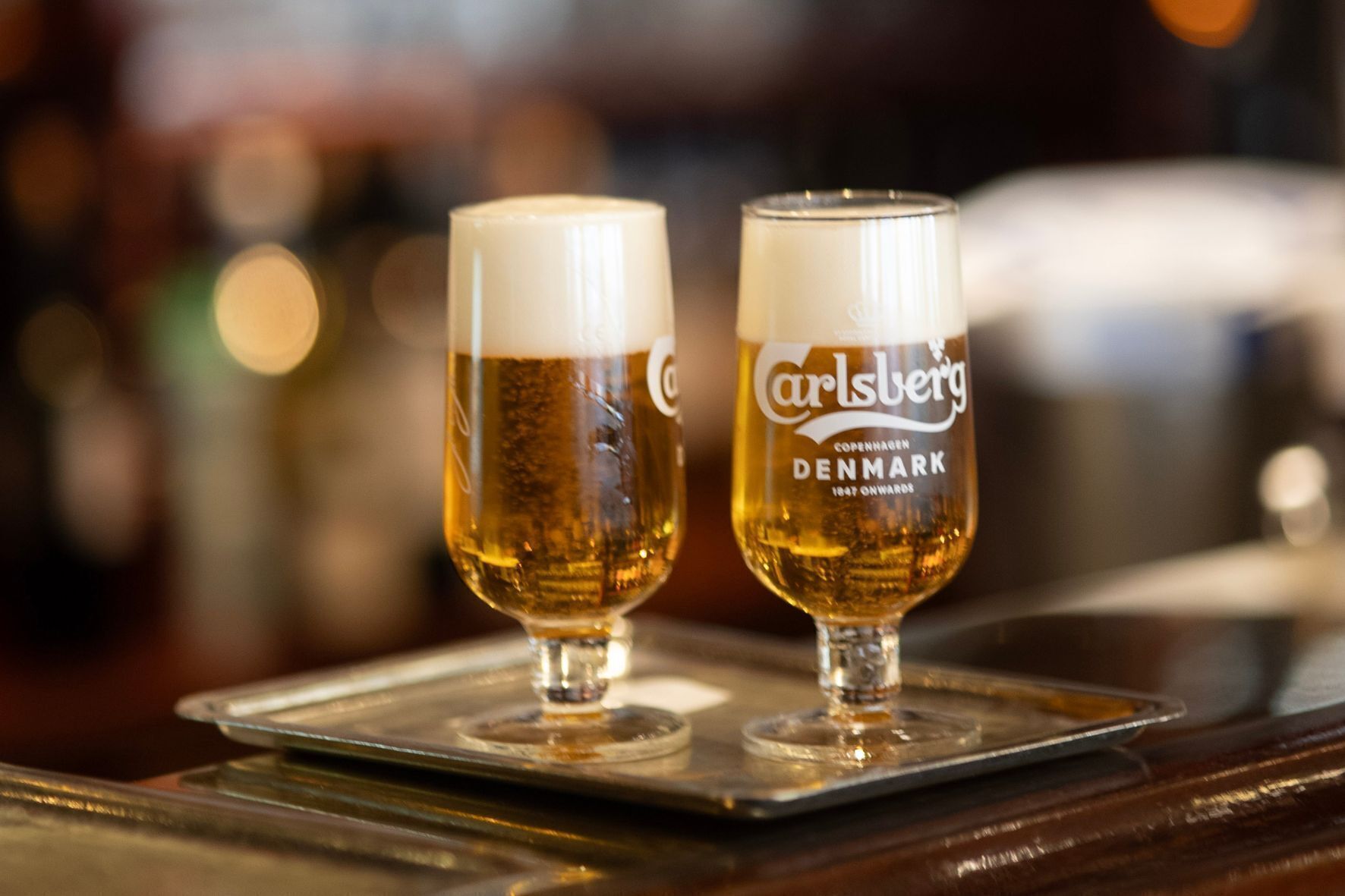 Dos vasos de cerveza sobre una bandeja.