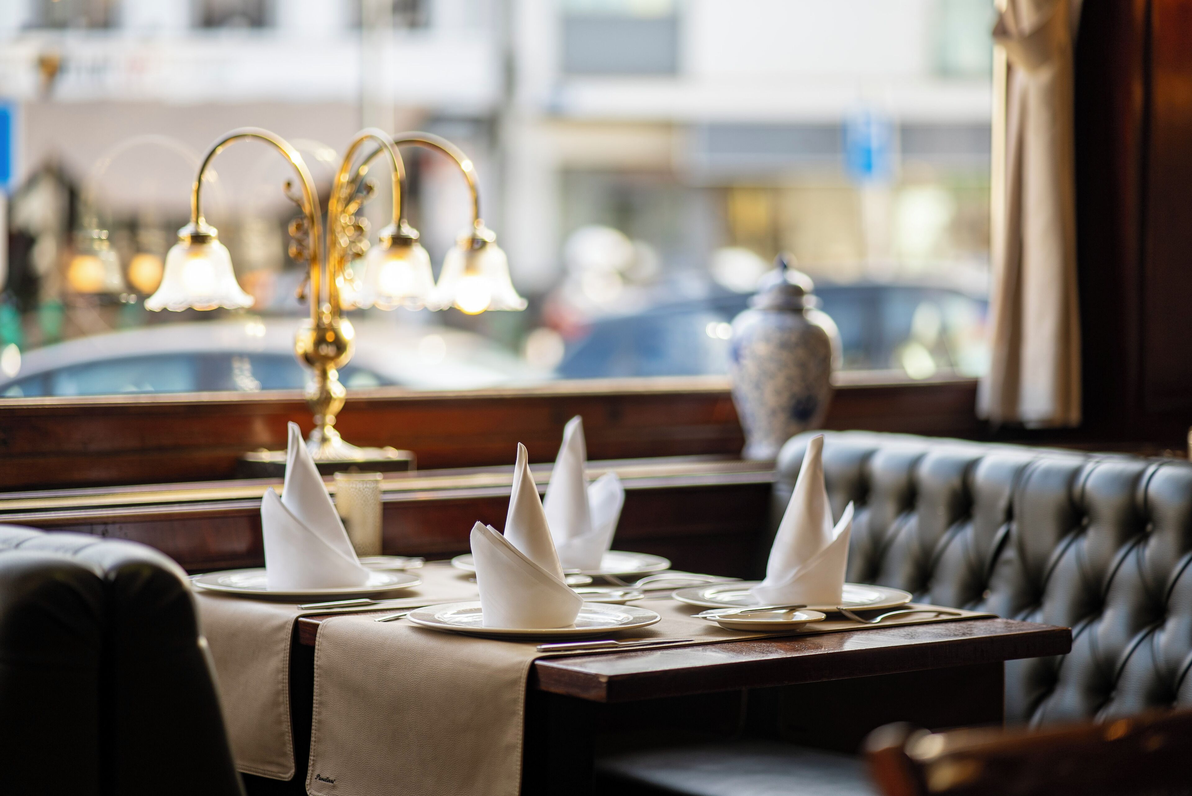 Un ambiente de restaurante con una mesa lista para comer, vista a la ventana y una lámpara decorativa.