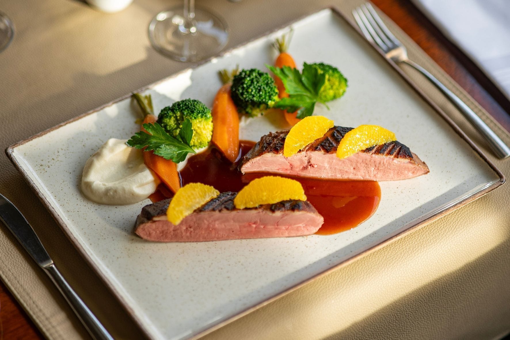 Un plat composé de viande, de légumes et de sauce, présenté sur une assiette en céramique.