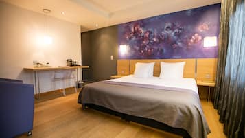 Una habitación de hotel moderna con una cama grande, un escritorio y una silla.