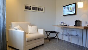 A modern living room with a sofa, a small table, and a bar area with stools. - Hôtel-Restaurant L’Auberge (Spa)