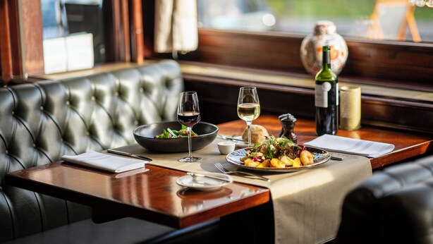 A dining table set with a salad, wine glasses, and a bottle of wine. - Hôtel-Restaurant L’Auberge (Spa)