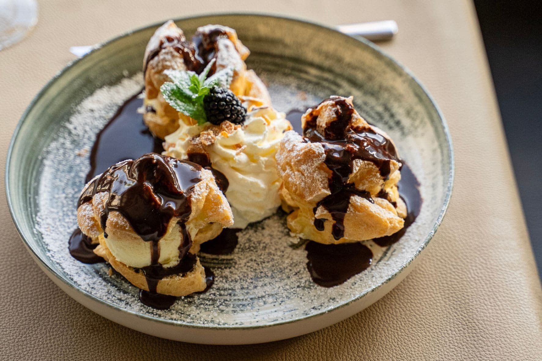 A dessert plate with chocolate sauce, ice cream, and a mint leaf garnish.
