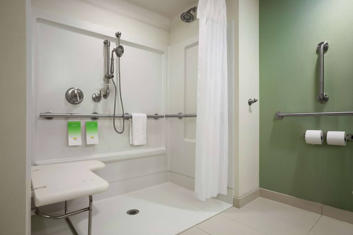 A modern bathroom with a shower, grab bars, a sink, and a toilet.