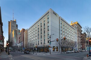 Um hotel com várias andares e fachada moderna, situado no cruzamento de ruas.