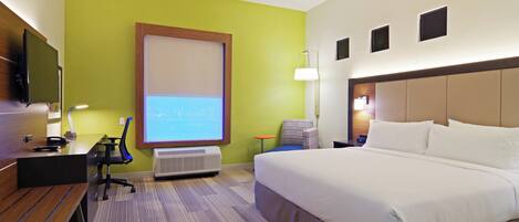 A hotel room with a bed, desk, chair, and a television.