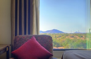A room with a view of a mountainous landscape through a window.