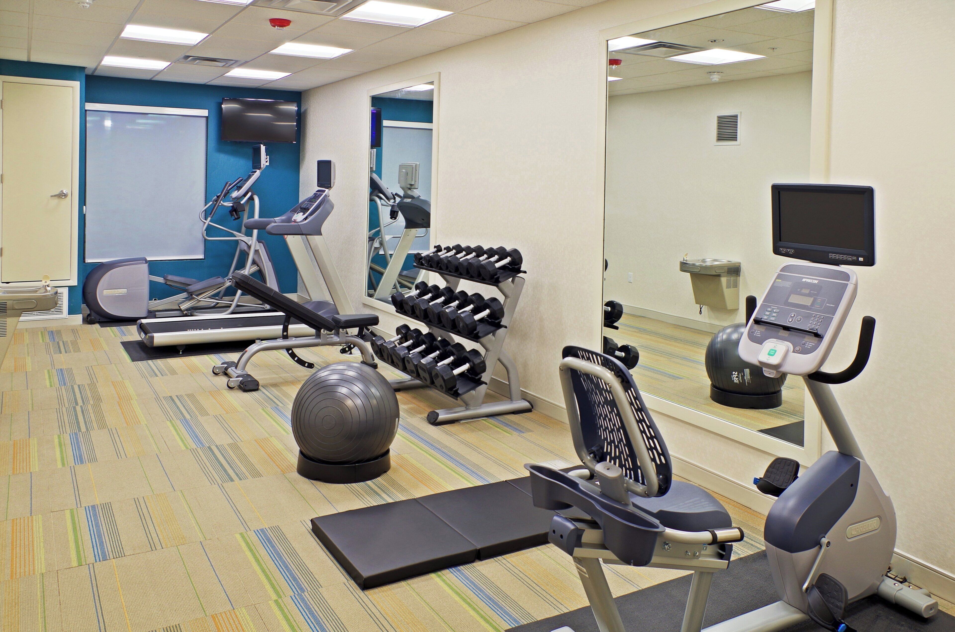 A fitness center with exercise equipment including treadmills, dumbbells, and a stationary bike.