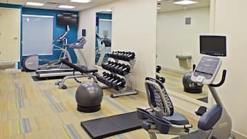 Un gimnasio con equipo de ejercicios, incluyendo cintas de correr, mancuernas y una bicicleta estática.