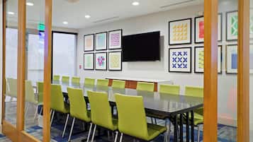 A conference room with a long table, green chairs, and framed artwork on the walls.