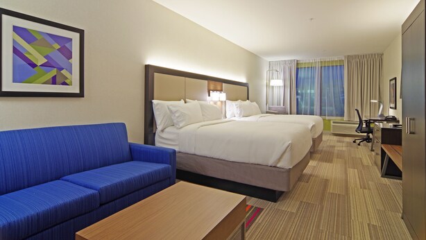 A hotel room with a large bed, a blue sofa, a wooden table, and a framed abstract painting on the wall. - Holiday Inn Express Hotel & Suites Phoenix North Scottsdale by IHG (Phoenix)