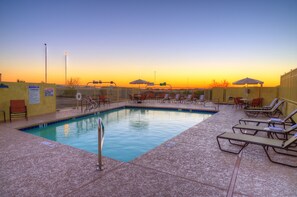 Een buitenzwembad, parasols bij het zwembad en ligstoelen