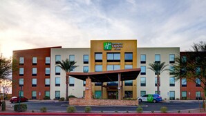 A Holiday Inn Express & Suites hotel with a modern design, featuring a central entrance with a covered walkway, multiple floors, and a parking area with a green and white car. - Holiday Inn Express Hotel & Suites Phoenix North Scottsdale by IHG (Phoenix)