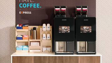A coffee station with two espresso machines, labeled 'Costa Coffee,' and a variety of coffee-related items on the counter.