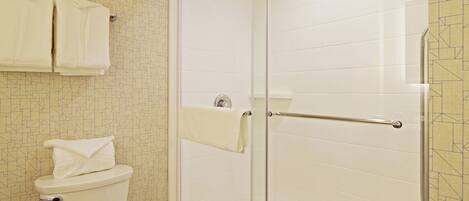 A bathroom with a toilet, a glass shower enclosure, and a towel rack.