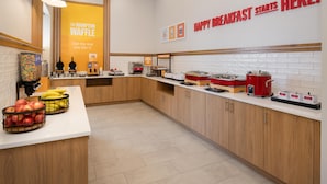 A modern kitchen with wooden cabinets, a white countertop, and a sign that reads "HAPPY BREAKFAST STARTS HERE." - Hampton Inn by Hilton North Hollywood (North Hollywood)
