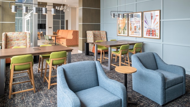 A modern hotel lobby with a mix of seating options including sofas, chairs, and a long table. - Hampton Inn by Hilton North Hollywood (North Hollywood)