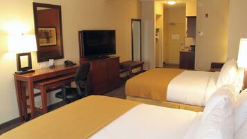 A hotel room with two beds, a desk, a television, and a mirror.