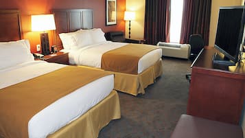 A hotel room with two beds, a desk, a television, and an air conditioning unit.