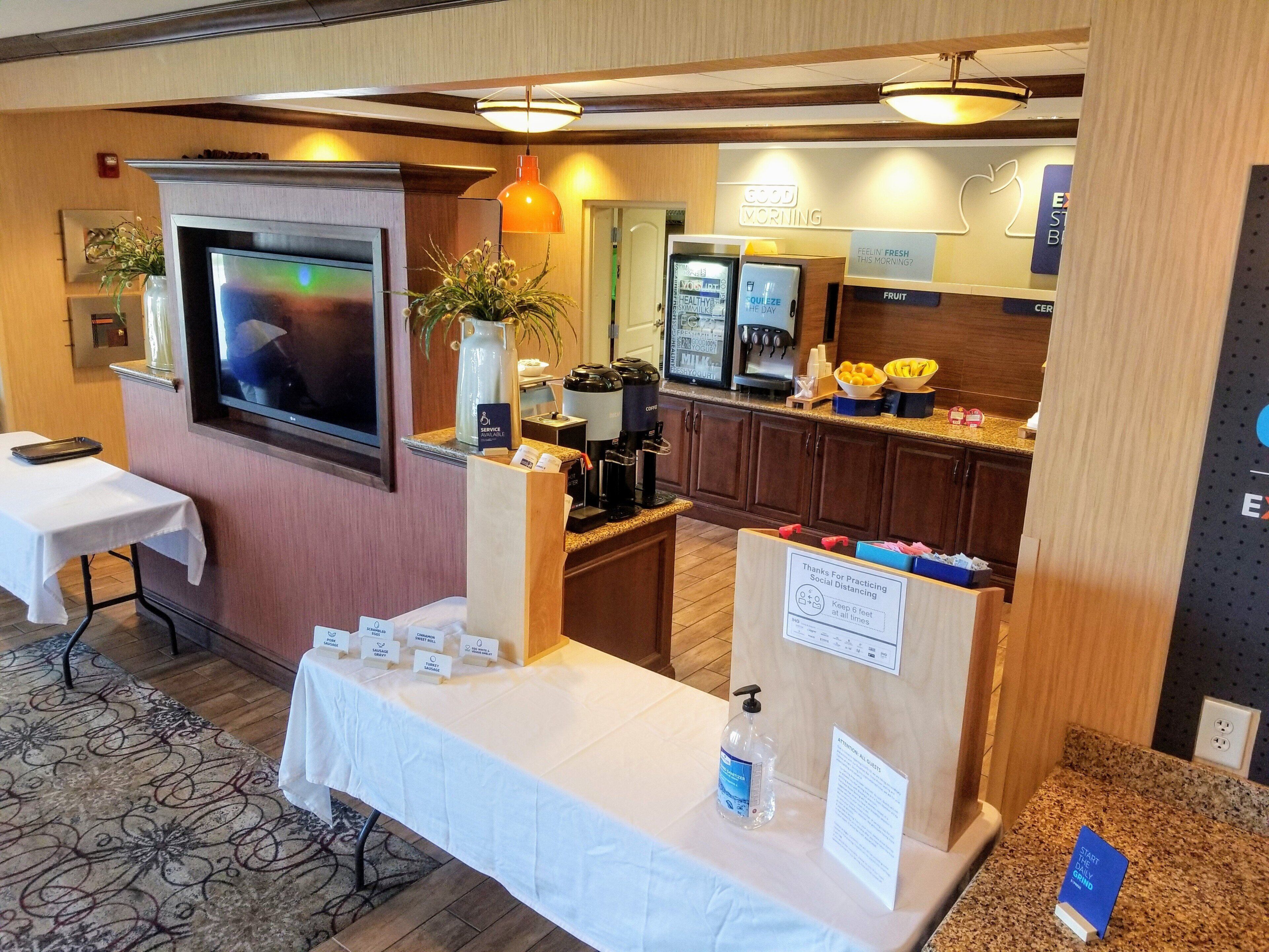 A hotel room with a television, a coffee machine, a fruit display, and a table with amenities.