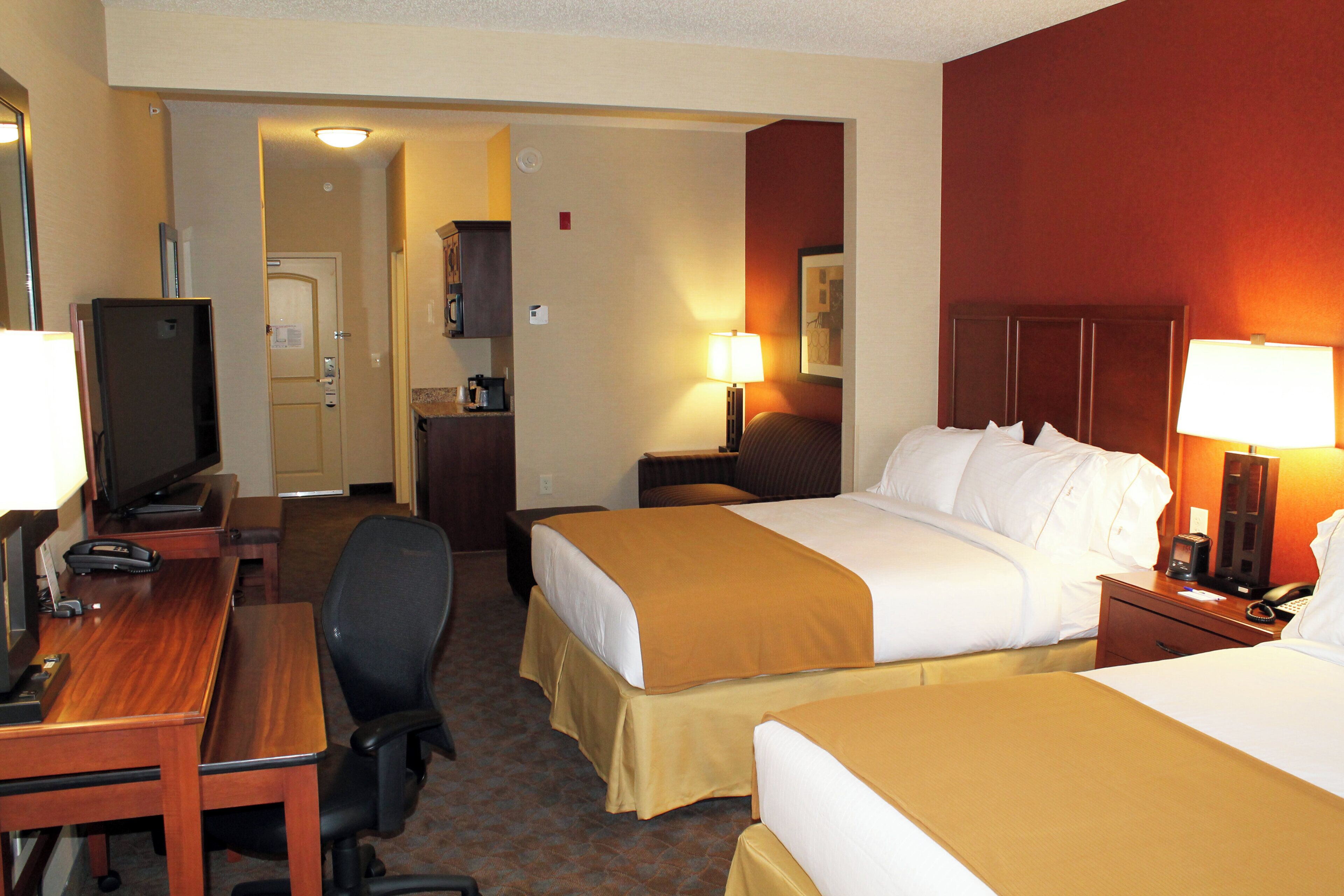 A hotel room with two beds, a desk, a television, and a telephone.