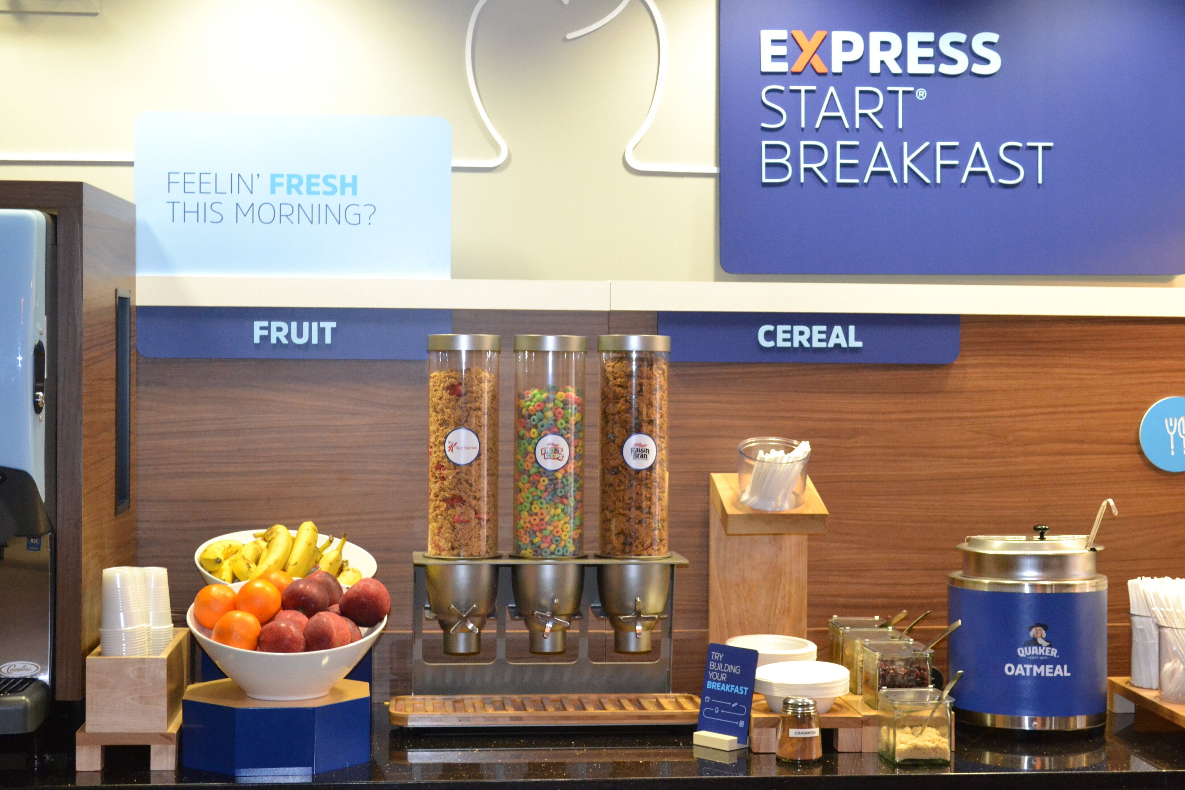 Zona de desayuno tipo buffet con secciones identificadas para fruta y cereales, que ofrece una variedad de opciones.