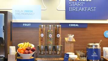 Zona de desayuno tipo buffet con secciones identificadas para fruta y cereales, que ofrece una variedad de opciones.