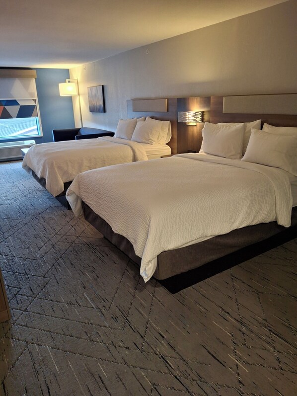 Une chambre d’hôtel avec deux lits, une grande fenêtre et un design moderne.