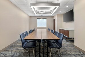 A conference room with a long table, chairs, a projector screen, and a large TV on the wall. - Holiday Inn Express Hotel & Suites Selinsgrove by IHG (Selinsgrove)