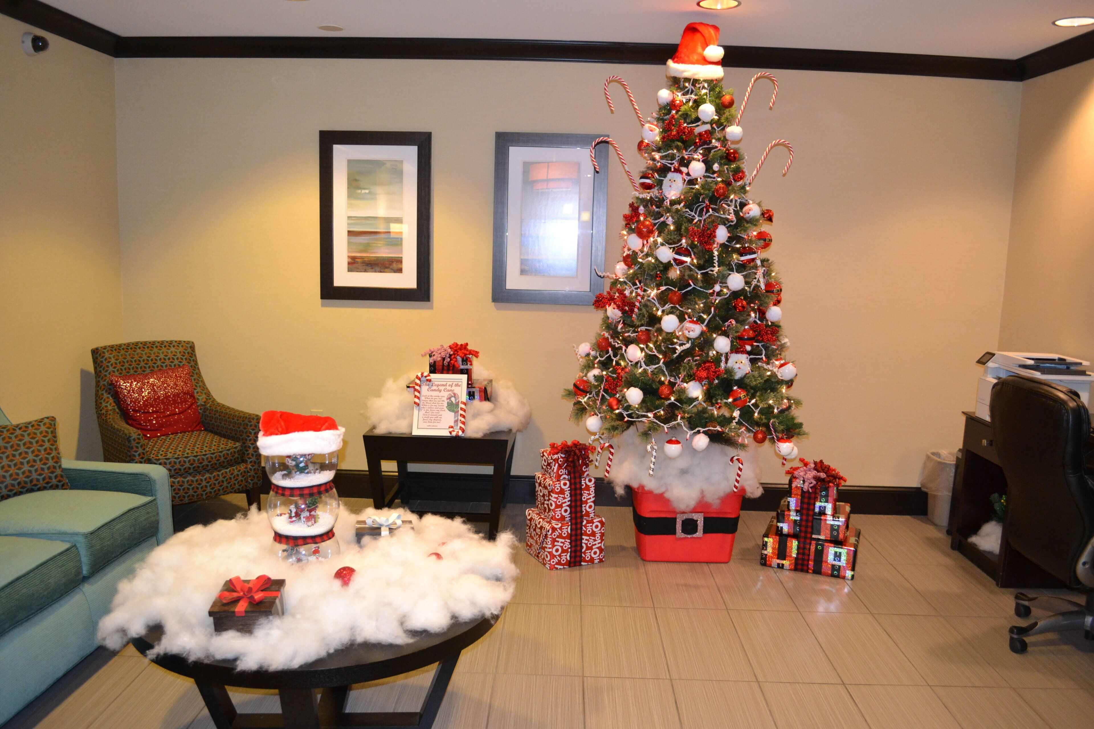 A room with a Christmas tree, a sofa, a table with a snowman decoration, and framed pictures on the wall.