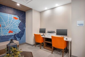 Um centro de negócios com duas mesas, cada uma com um computador e monitor, e um mapa mural grande.