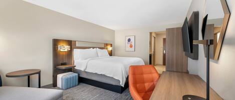A hotel room with a bed, a desk, a chair, a TV, and a small table.