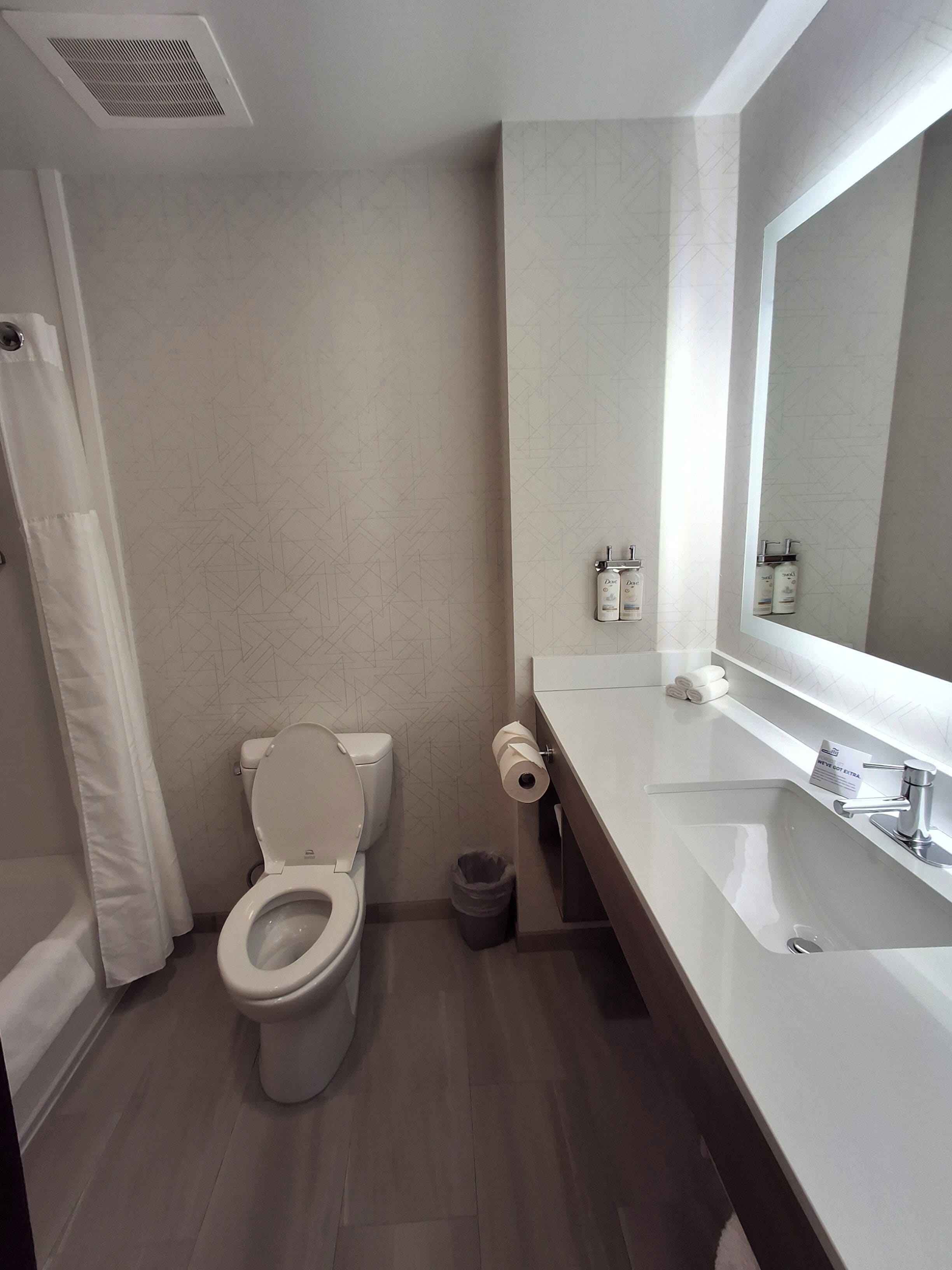 A modern bathroom with a toilet, a sink, and a mirror.