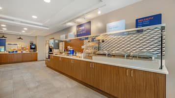 A breakfast area with a self-service station, including cereal, hot food, and a bakery section.