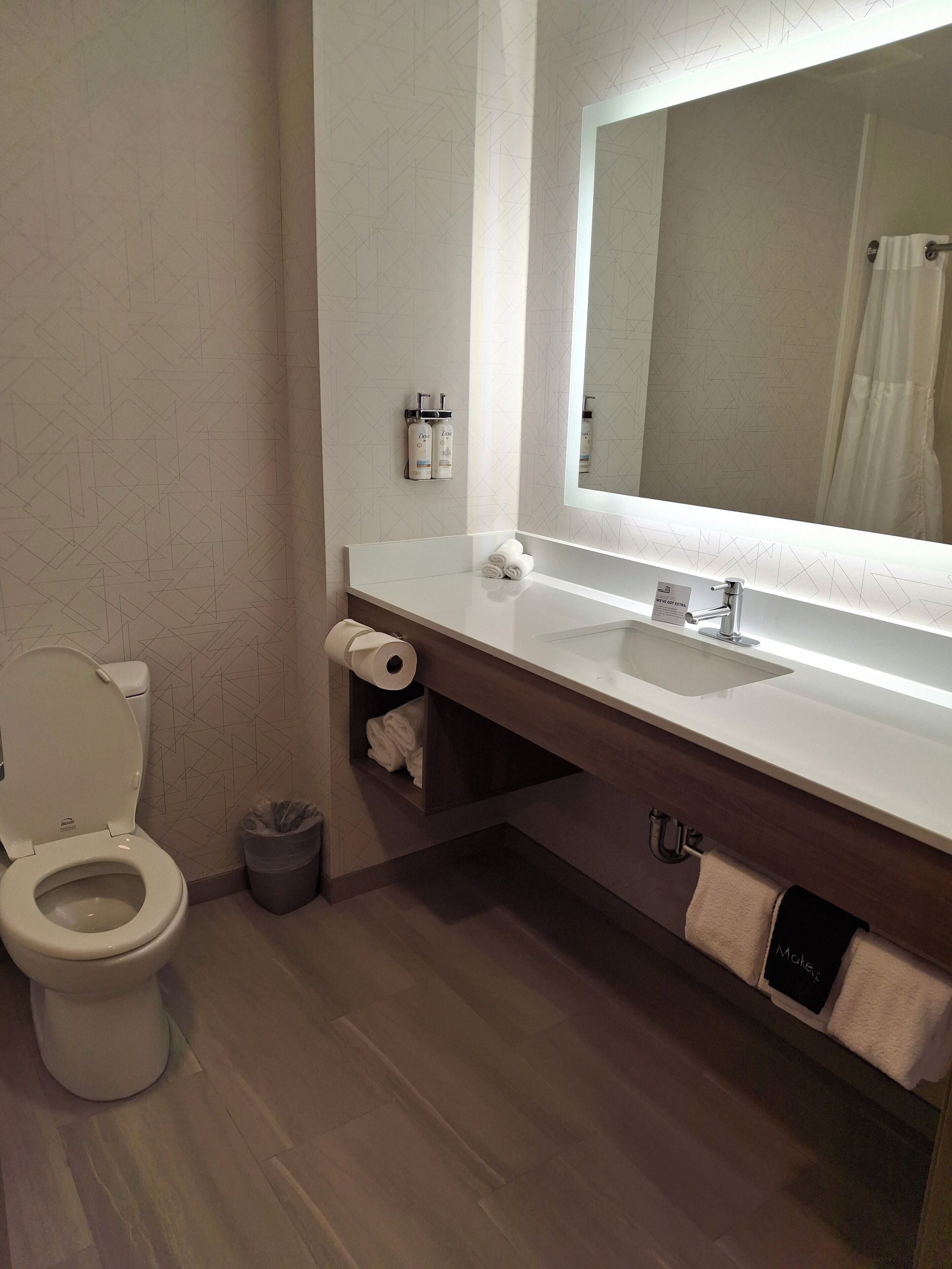 Une salle de bain moderne équipée d’un WC, d’un lavabo, d’un miroir et d’un porte-serviettes.